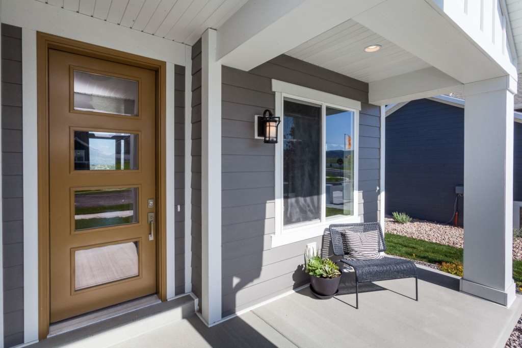 A close up shot of a front entryway and chair and plant sitting on a porch area of a newly remodeled home