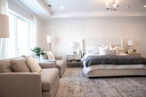 large white and grey master bedroom with king size bed and two cushion chairs