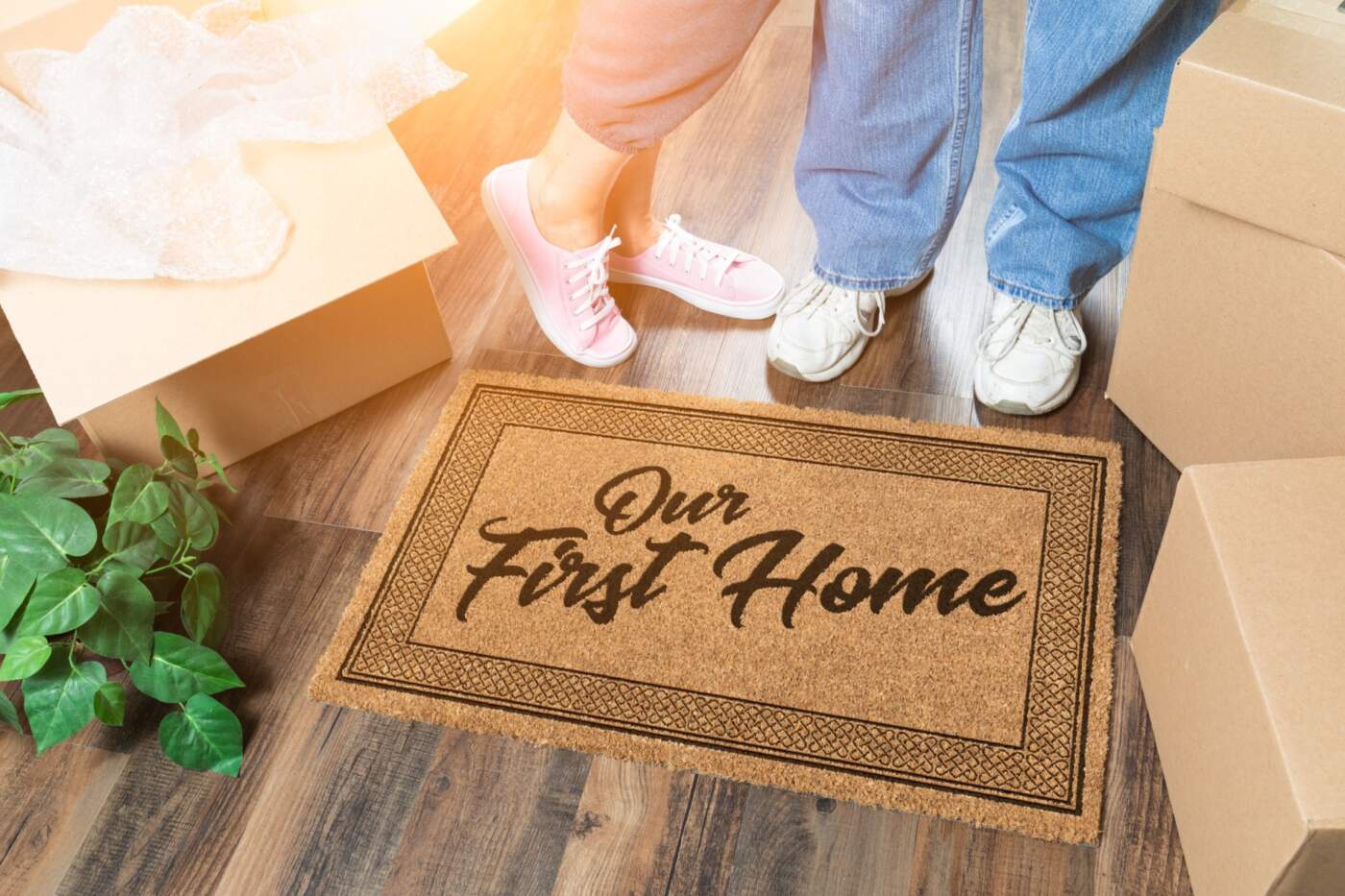 picture of a welcome mat with the words "our first home" at the feet of people unpacking