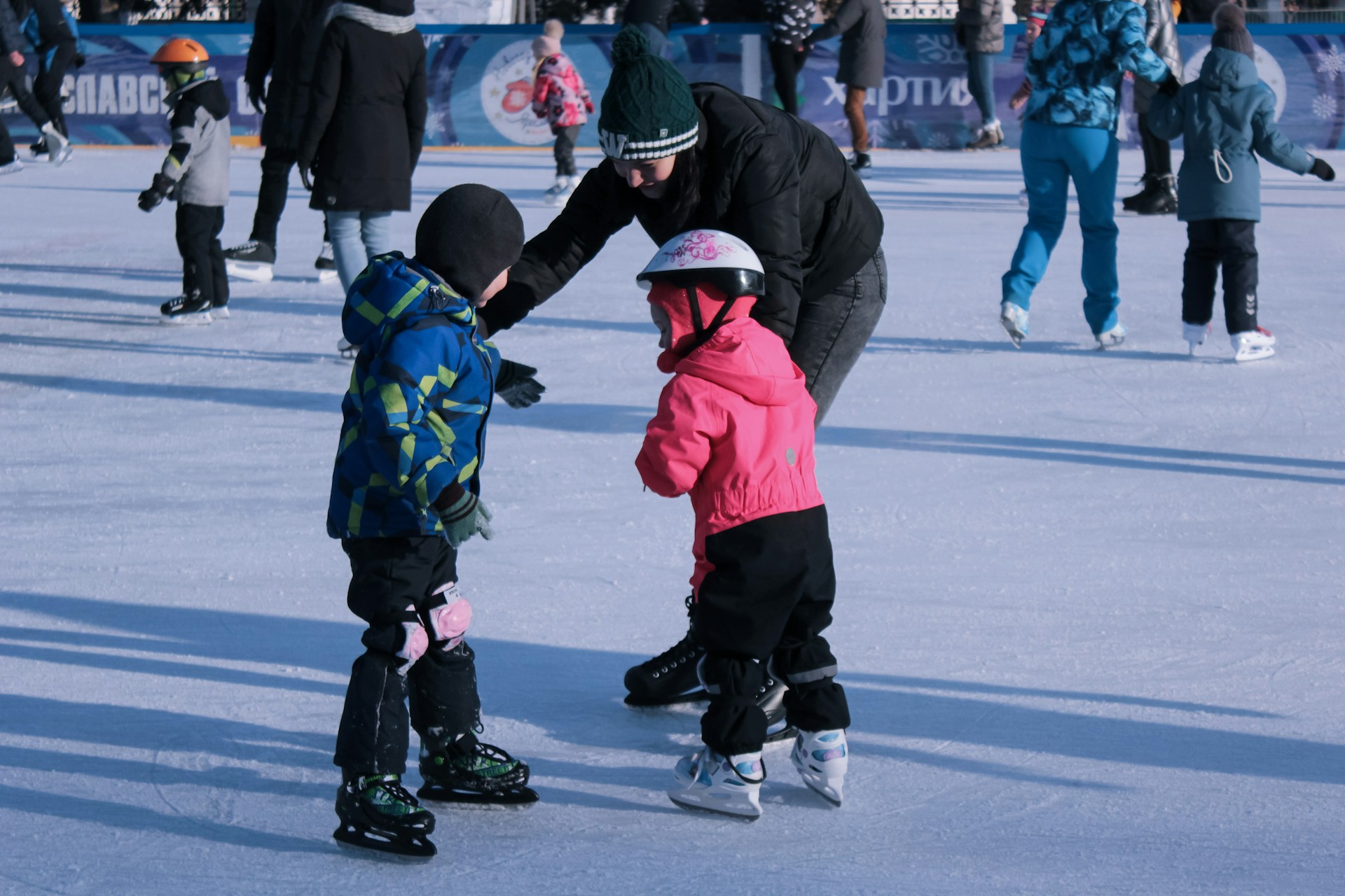Mother with two children ice skating at a rink, one of the best winter activities in Utah