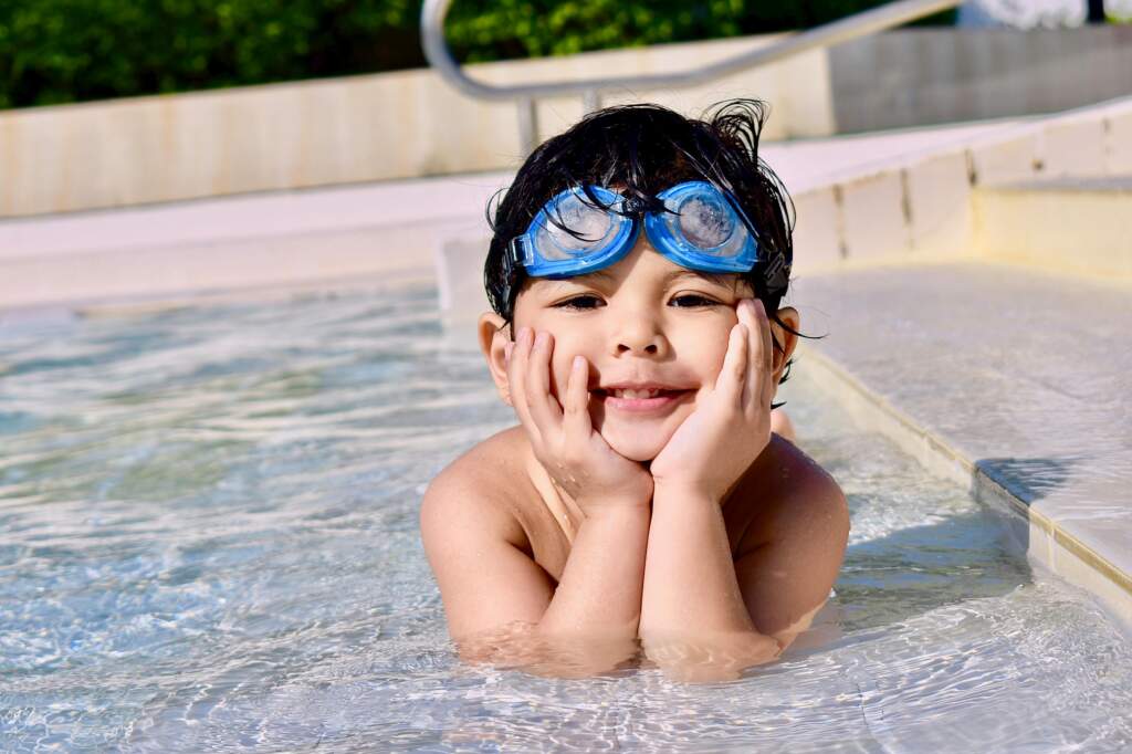 A young boy wearing swim goggles in a swimming pool at a rec center in Utah