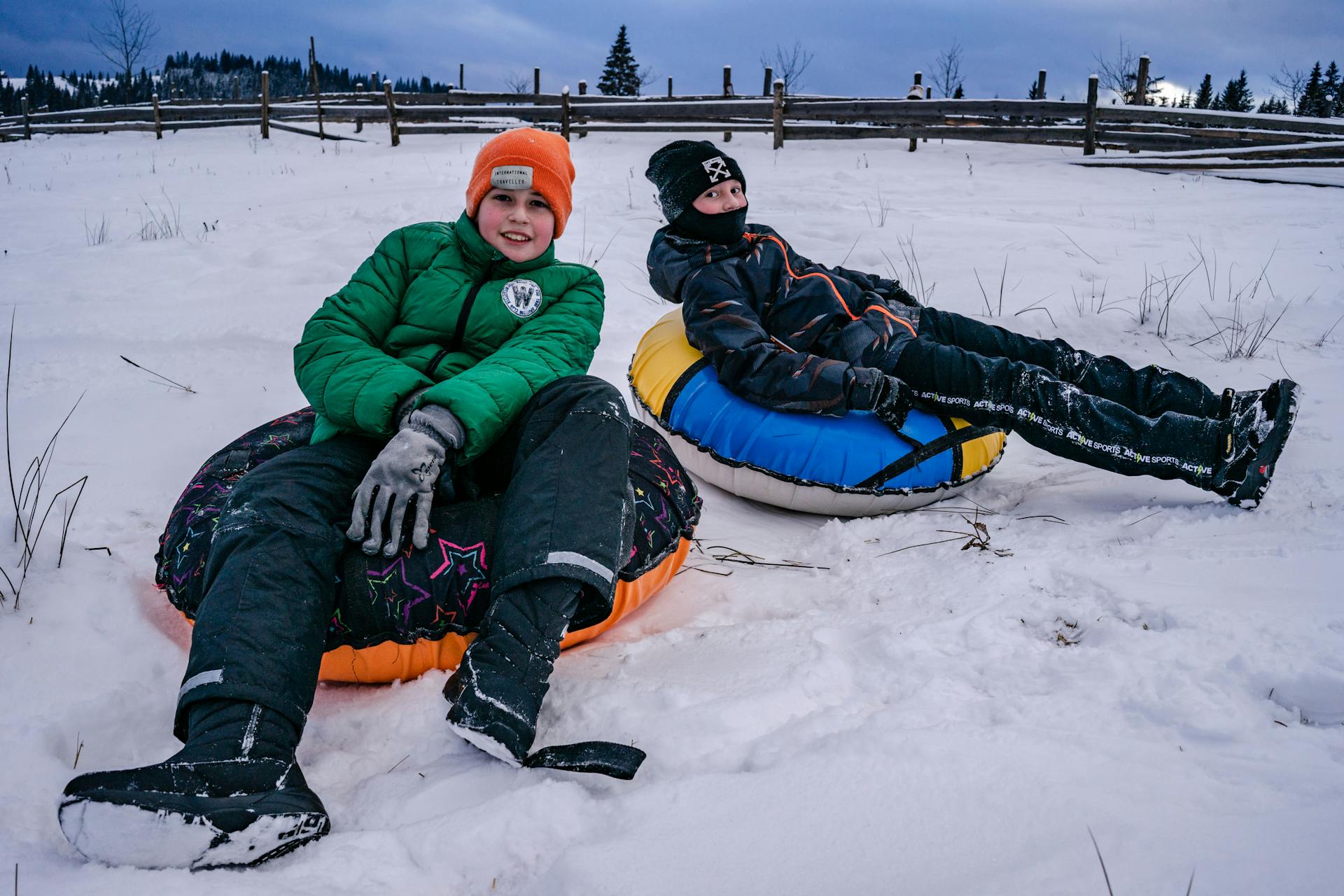 Two boys sitting on snow tubes, one of the best winter activities in Utah