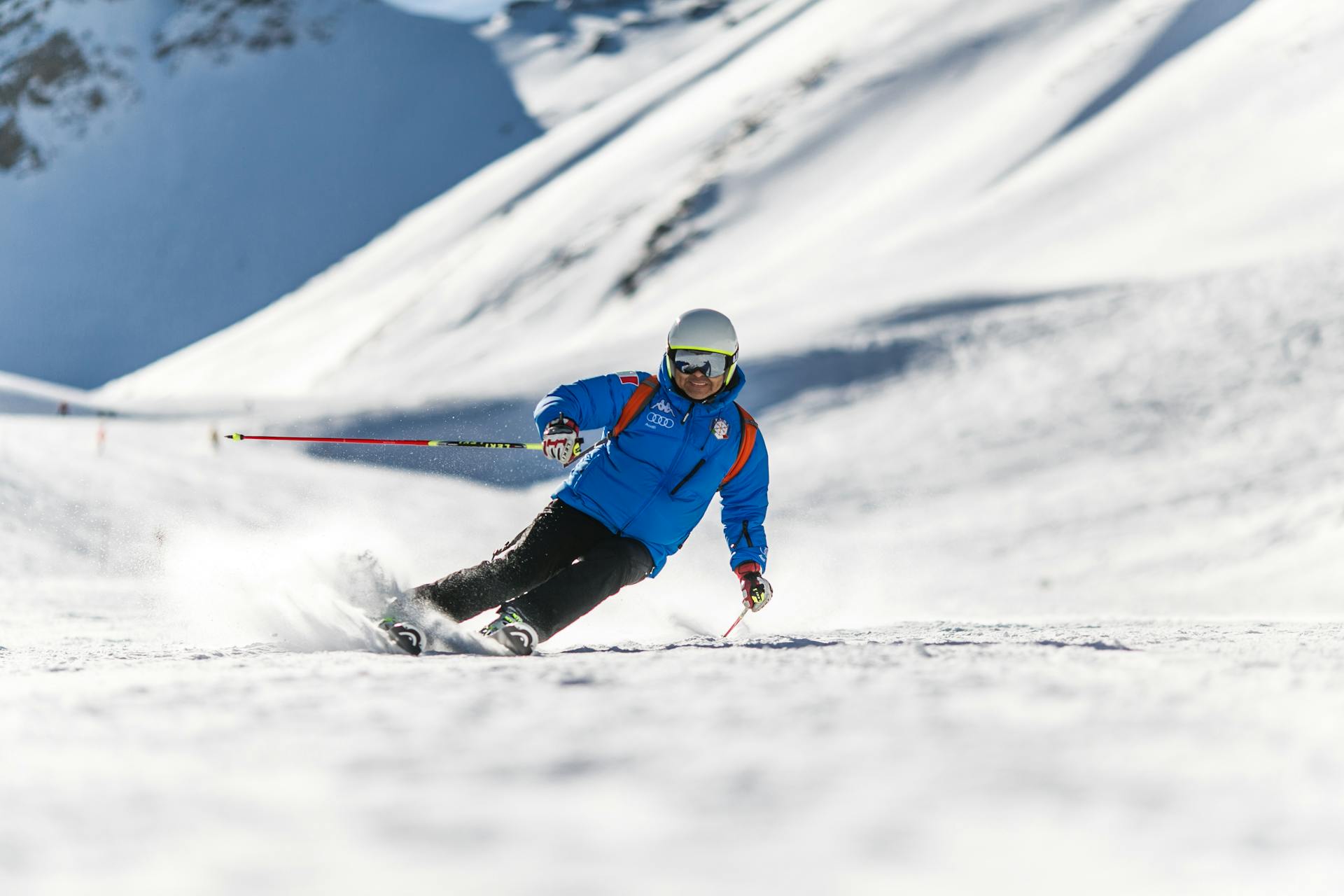 Man in blue ski coat skiing down mountainside, one of the best winter activities in Utah