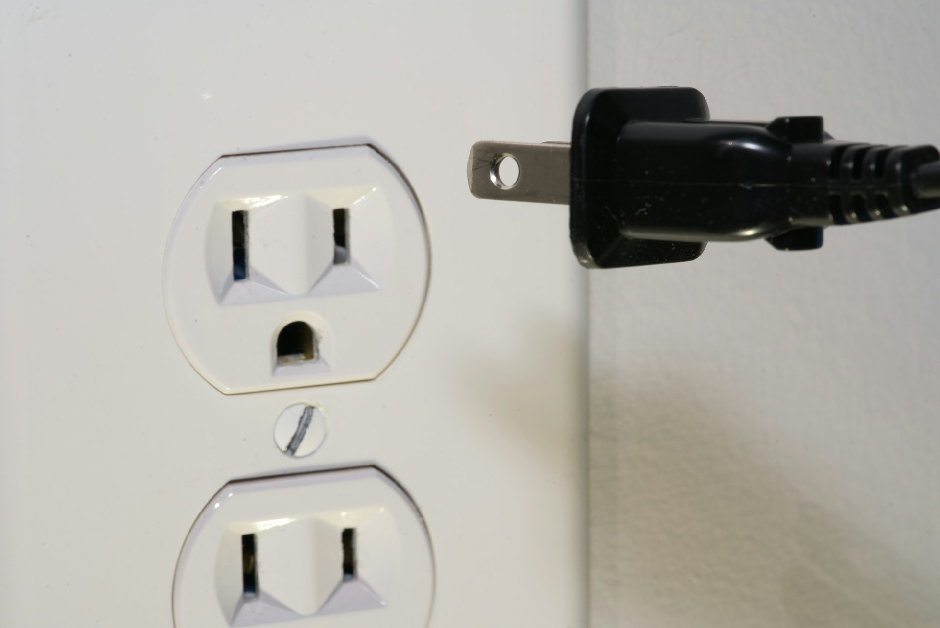 Someone about to plug an appliance in and test an electrical outlet after de-winterizing a home