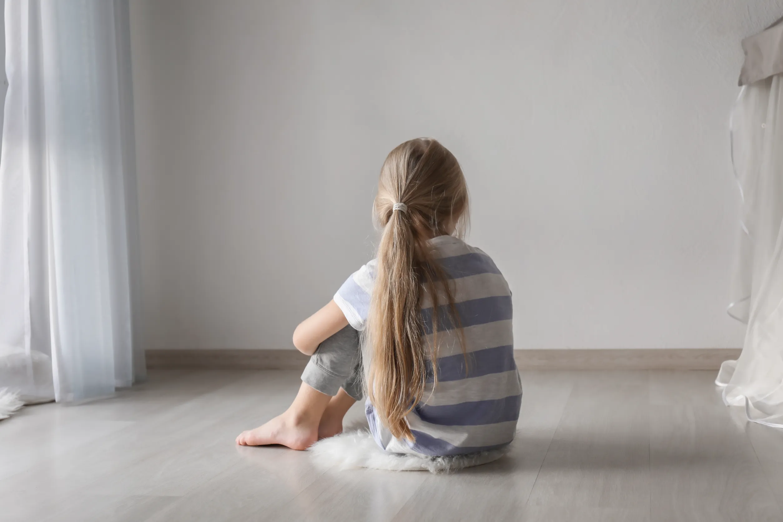 Lonely child sitting on her bedroom floor